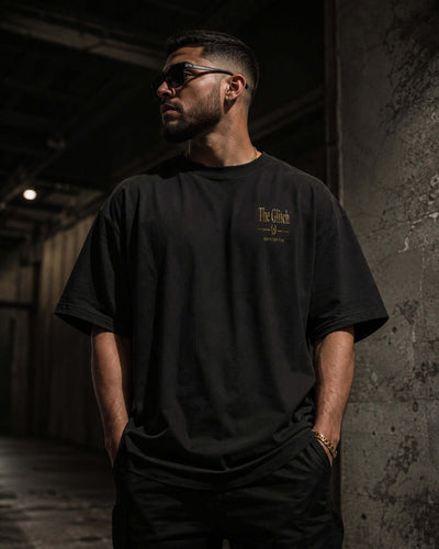 Man wearing THE GLITCH back print oversized tee with front logo in an urban setting.