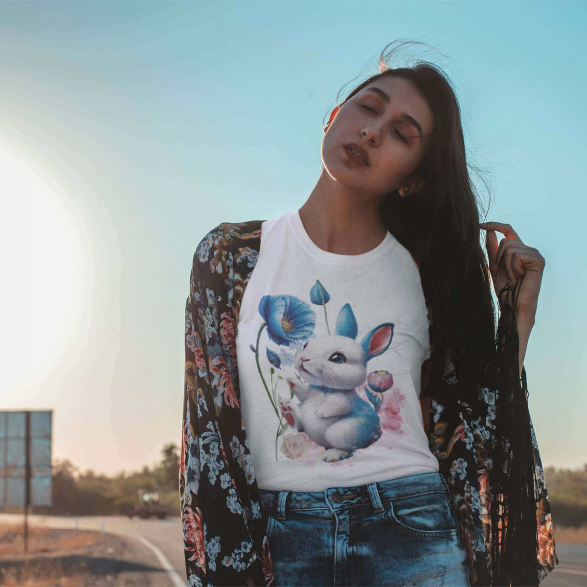 A model wearing a floral bunny t-shirt featuring a watercolor bunny design surrounded by blue poppies.